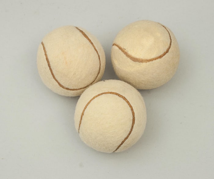 Três bolas de tennis brancas revestidas de feltro