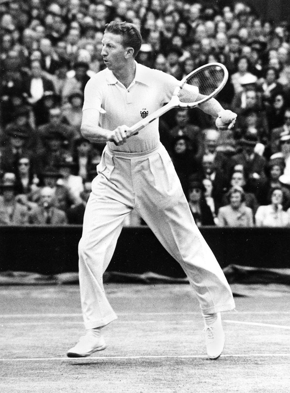 Don Budge em ação em Wimbledon, com o estádio lotado ao fundo