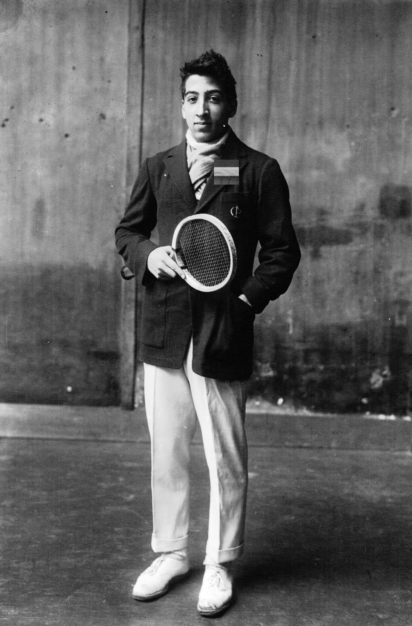 René Lacoste em 1922, de blazer, segurando a raquete