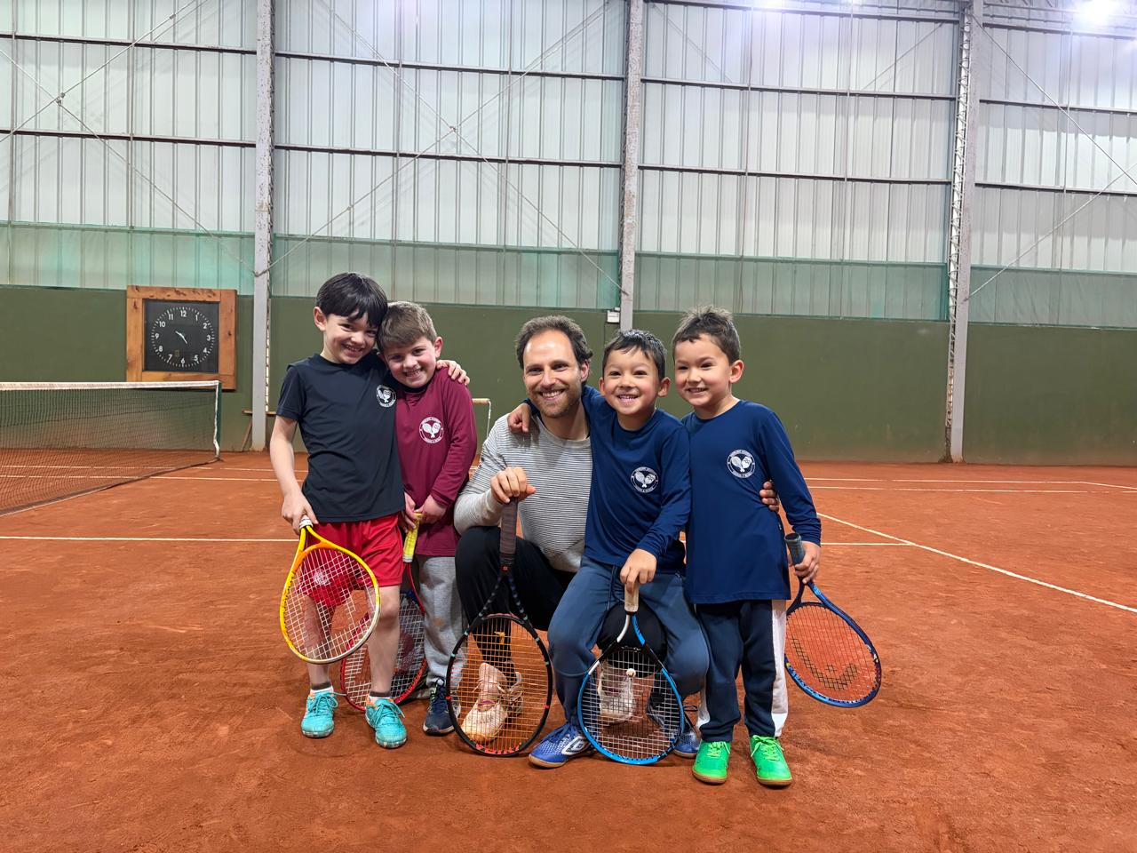 Lucas Ghisleni com uma turma de tennis infantil na quadra de saibro